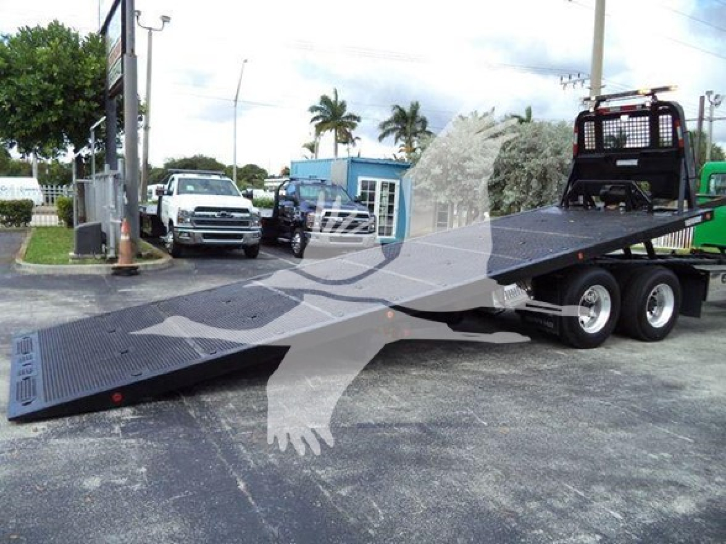 2014 Peterbilt 367 rollback truck with a long flatbed ramp extended on a parking lot; cab visible in background; no legible small text detected on components.
