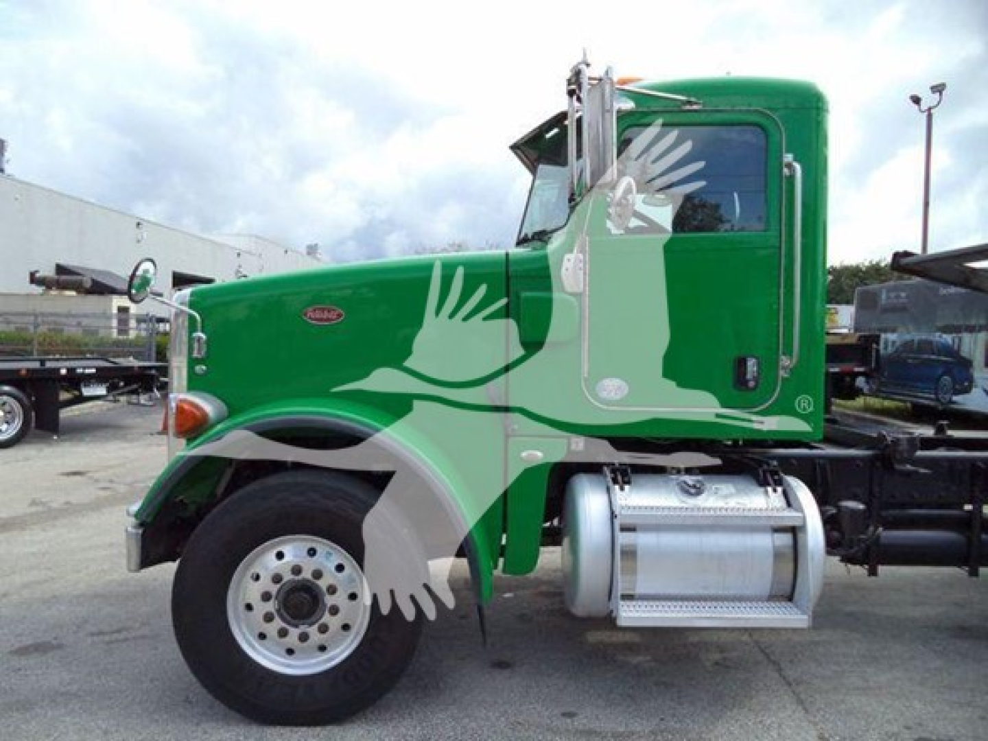Peterbilt 367 truck cab in green with side fuel tank, two white wheels, fuel tank, and step; visible branding shows Peterbilt badge on the door.