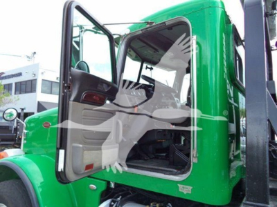 Cab entry of a green Peterbilt 367 rollback truck showing open door and interior cab details.