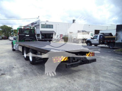 2014 Peterbilt 367 rollback truck and flatbed in a lot; rear view showing flatbed with trailer hitch, triple-axle rear, reflective chevrons.