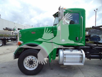 Peterbilt 367 truck cab in green with side fuel tank, two white wheels, fuel tank, and step; visible branding shows Peterbilt badge on the door.