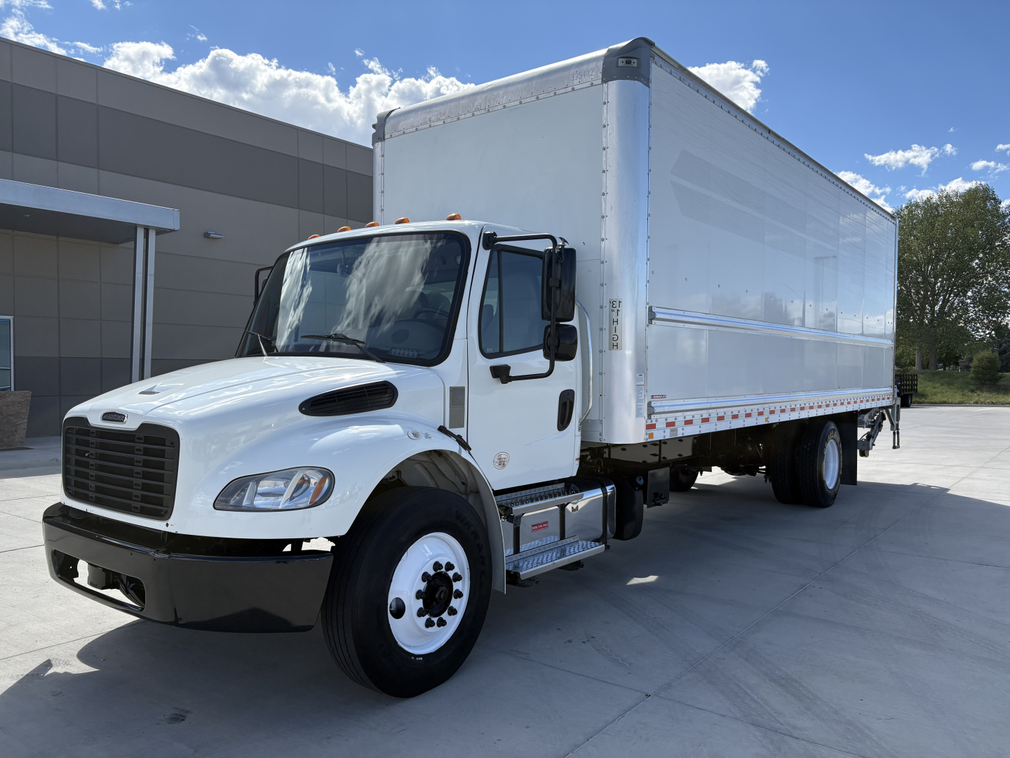 2022 Freightliner M2-106 box truck with white cab and cargo box, side view showing front grille, dual rear wheels, and reflective side trim.