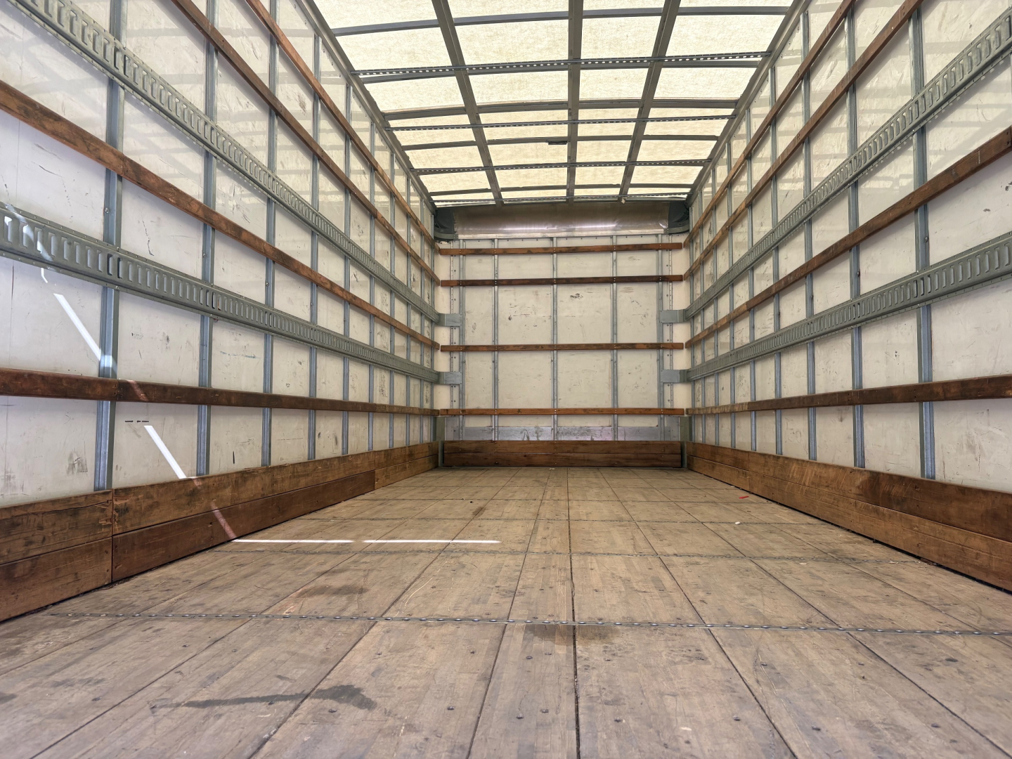 Freightliner M2-106 box truck cargo area showing empty wooden floor and side rails.
