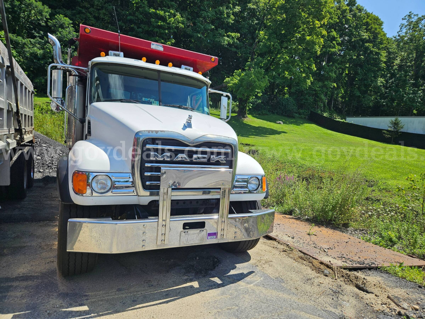 2007 Mack CV713 dump truck front view showing chrome bumper and red dump body
