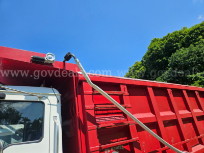 Mack CV713 dump truck cab and red dump body with watermarked background and blue sky