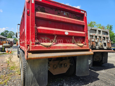 Rear view of a red 2007 Mack CV713 dump truck showing dump bed tailgate, chains, mud flaps, and dual rear wheels.