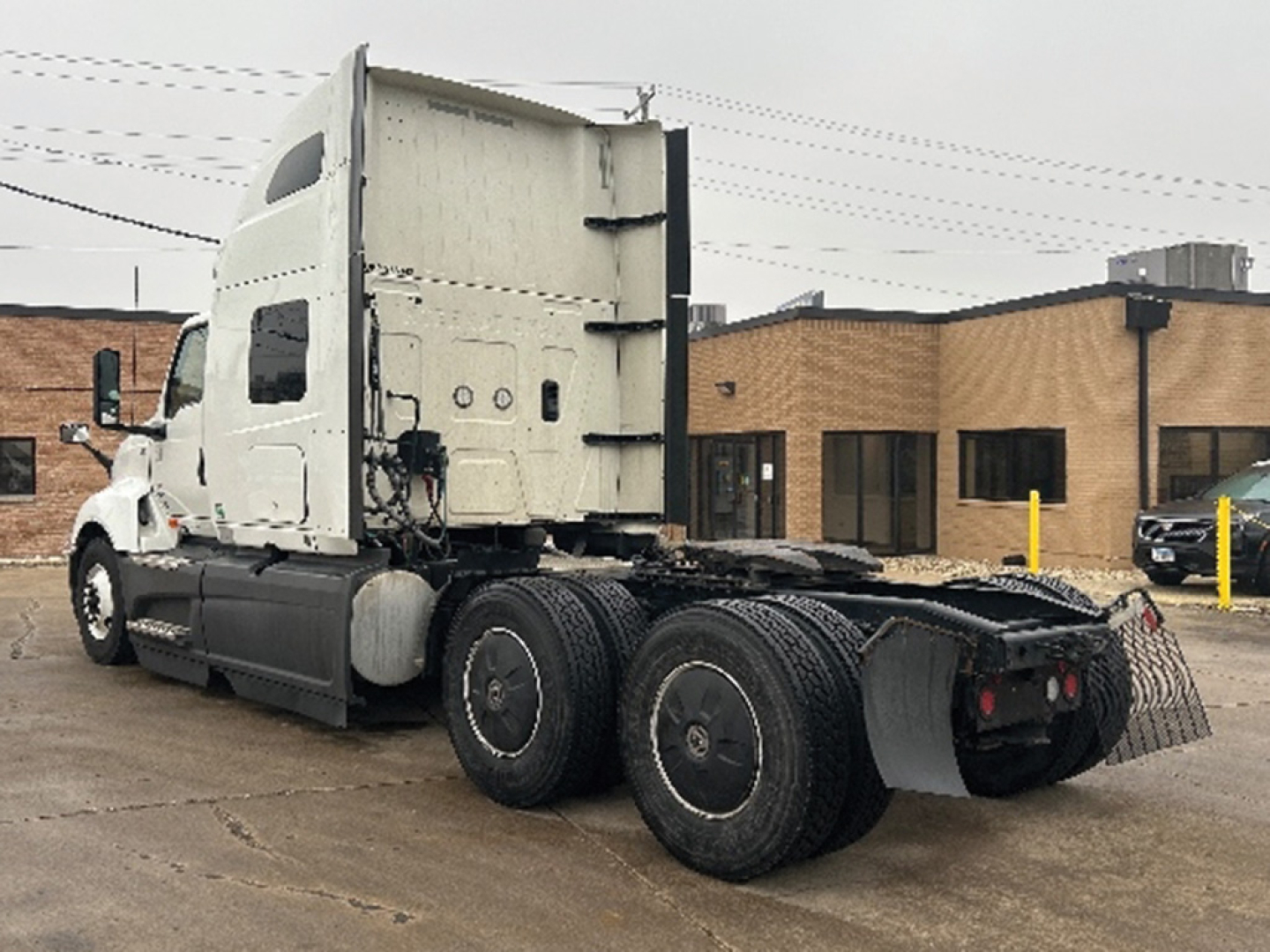 Truck tractor side and rear with sleeper cab, LT625 badge not visible, white exterior, dual rear axles, fifth wheel area, surrounding dealership lot.