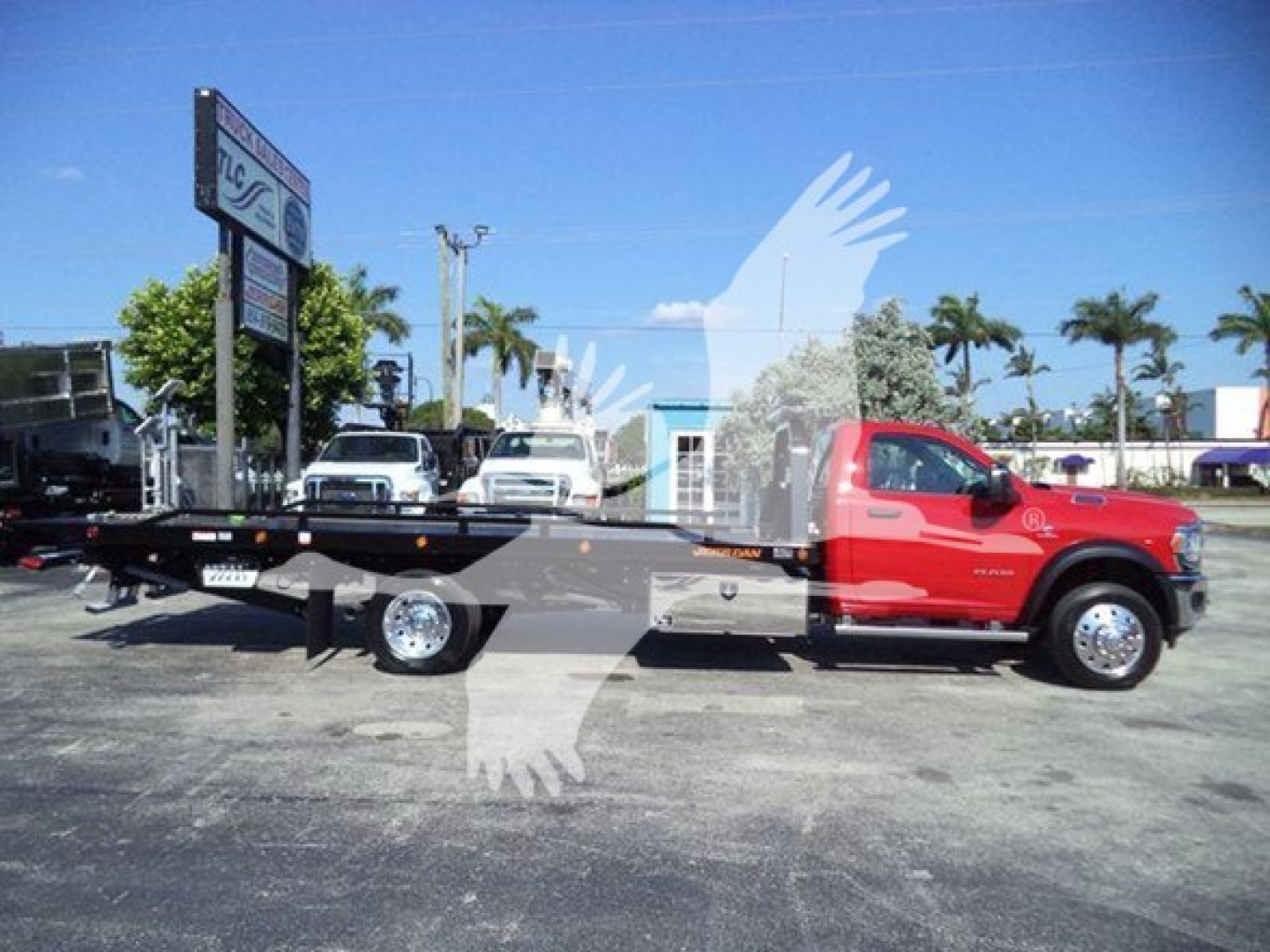 Ram 5500 rollback truck side view showing red cab and long black flatbed with chrome wheels and diesel engine badge.