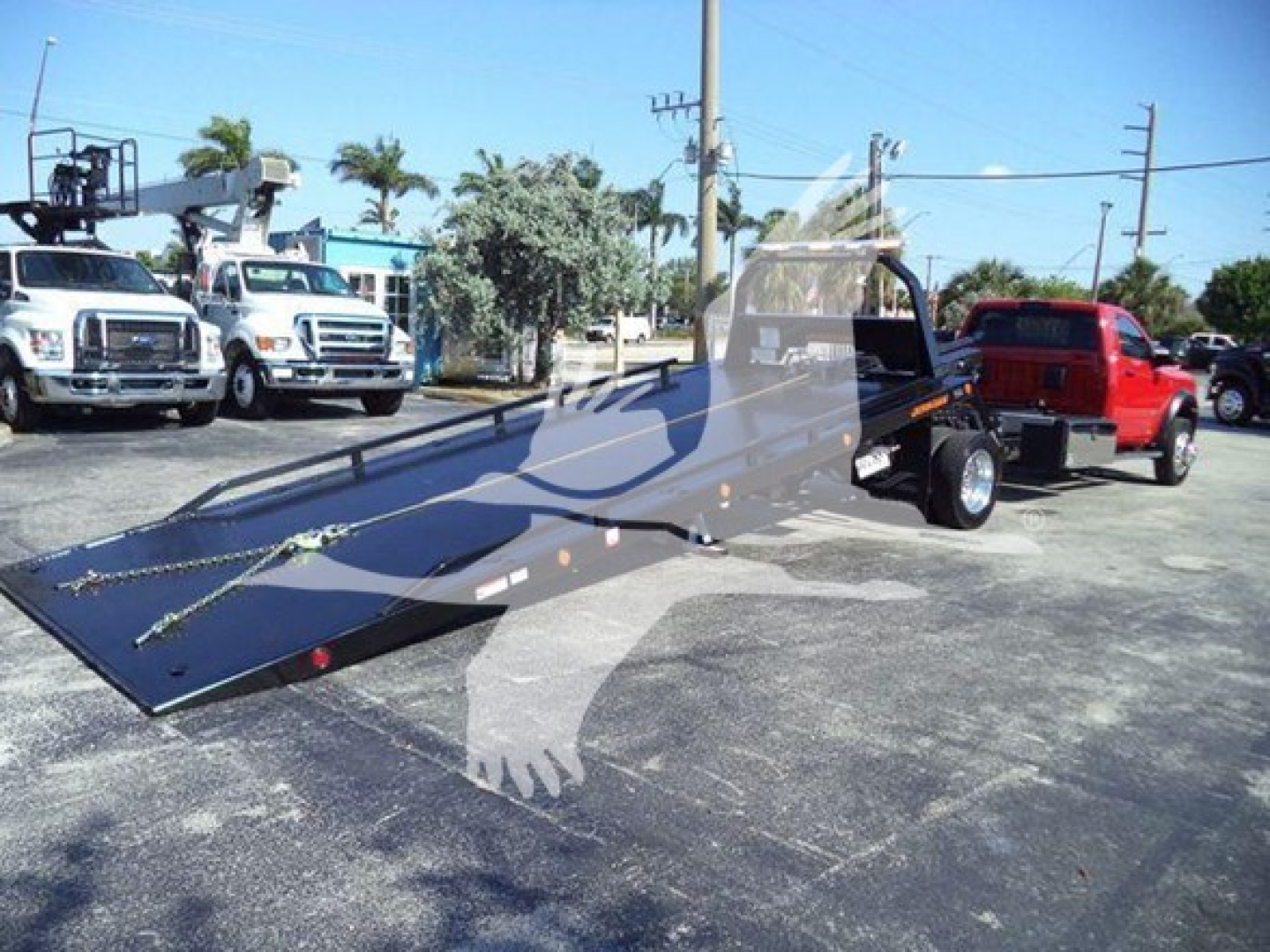 Ram 5500 rollback tow truck flatbed in service bay showing loading ramp with red pickup in background