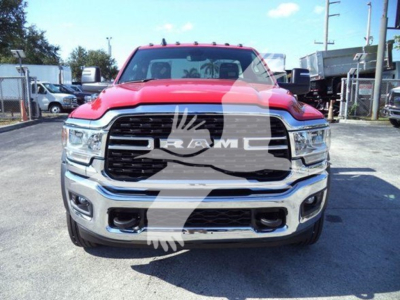 Ram truck front view showing grille with RAM badge and chrome bumper, red hood and headlights visible.