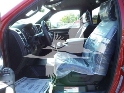 Ram 5500 interior view showing front bench seat and plastic protective covers on seats, steering wheel, dashboard, and pedals; red exterior visible from open driver door.