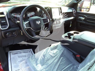 Ram 5500 interior showing steering wheel with RAM logo, dashboard, touchscreen display, center console, and front passenger seat wrapped in plastic.