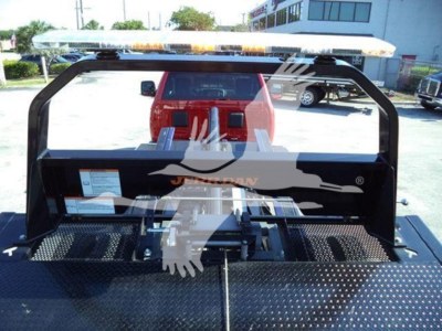Ram 5500 rollback bed showing metal frame and orange warning light bar on top with red cab in background.