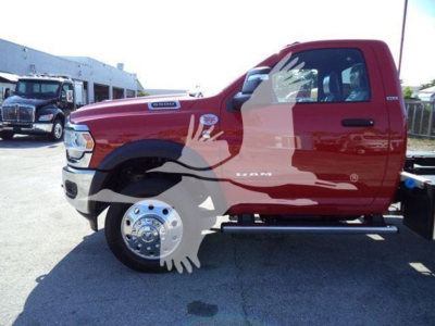 Ram 5500 pickup side view showing red cab with chrome wheel, running boards, and sticker labels on fender; front wheel visible