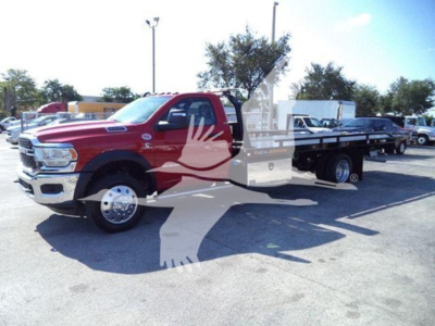Ram 5500 towing truck in red, front grille and flatbed visible, dealer lot in background.