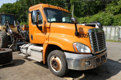 Orange Freightliner Cascadia 125 daycab truck in a lot showing front grille, cab, and front wheel; number 1005 on door.