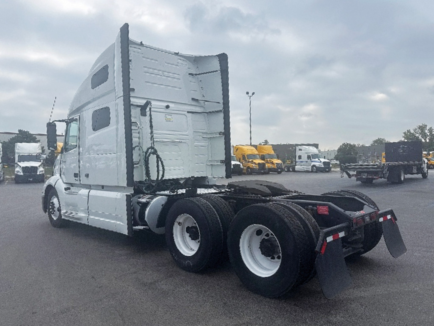 Volvo VNL 760 truck in a yard showing side view with sleeper cab and dual rear axles; wheel wells and mudflaps visible.