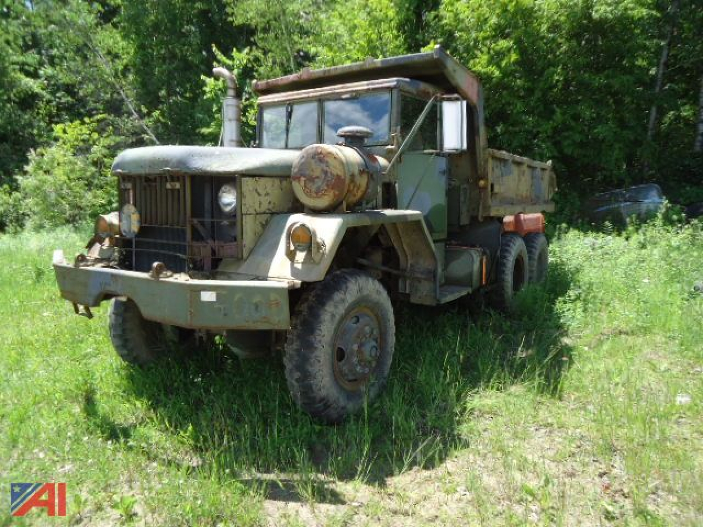 Jeep Kaiser XM817 W0/W dump truck in field with green foliage, olive drab paint, rugged tires, front grille, and dump bed visible