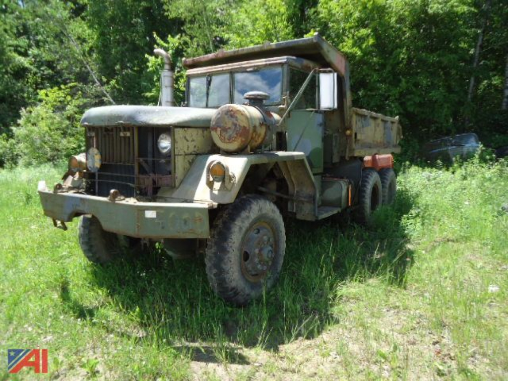 Jeep Kaiser XM817 W0/W dump truck in field with green foliage, olive drab paint, rugged tires, front grille, and dump bed visible