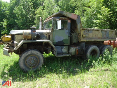 1960 Jeep Kaiser Jeep 5 Ton XM817 W0/W Dump Truck with camouflage cab and rusty dump bed in a grassy area.