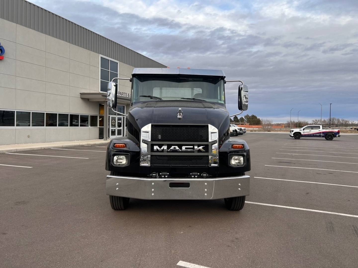 Mack MD6 truck front view showing bold grille with MACK letters and chrome bumper in outdoor lot.