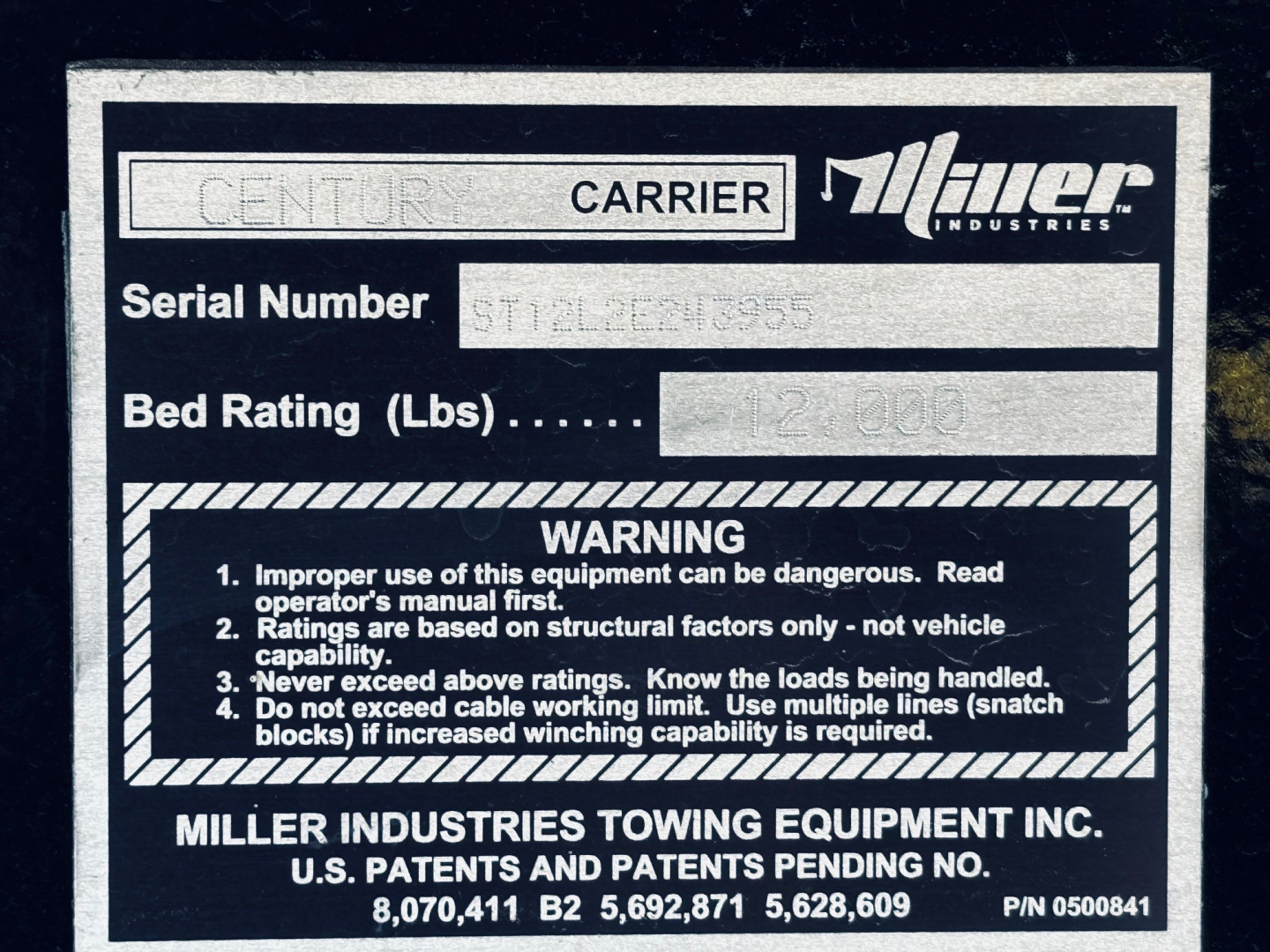 Miller Industries Tow label on a Century Carrier showing Serial Number and Bed Rating (lbs) with warning box.