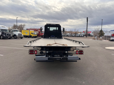 Flatbed tow truck on lot with rear view showing platform and taillights, 2025 Mack MD6 in listing context.