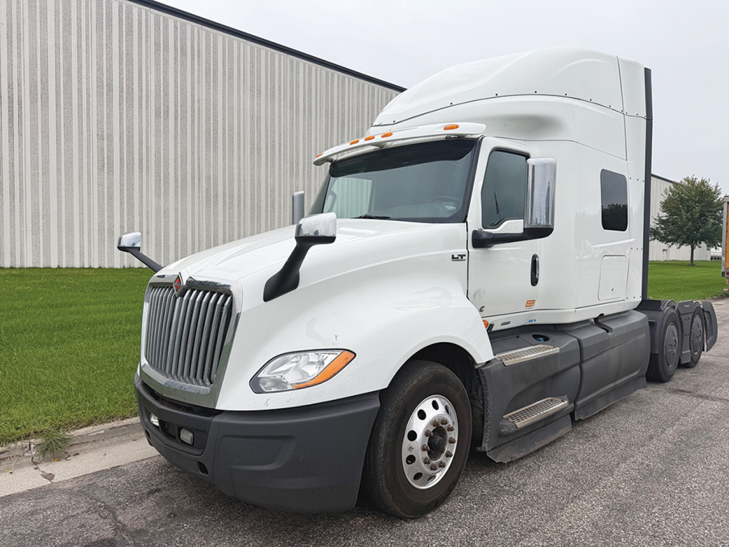 International LT625 sleeper tractor in white, side view showing cab, grille, headlights, and dual rear axles.