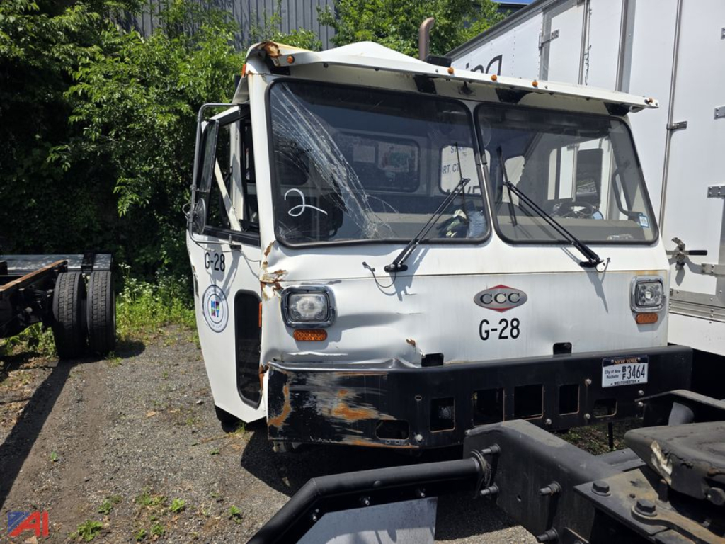 Cab and chassis truck front view with Crane Carrier LET2-46 cab identifiers G-28 and CCC badge, front bumper with hitch, weathered paint and rust showing.