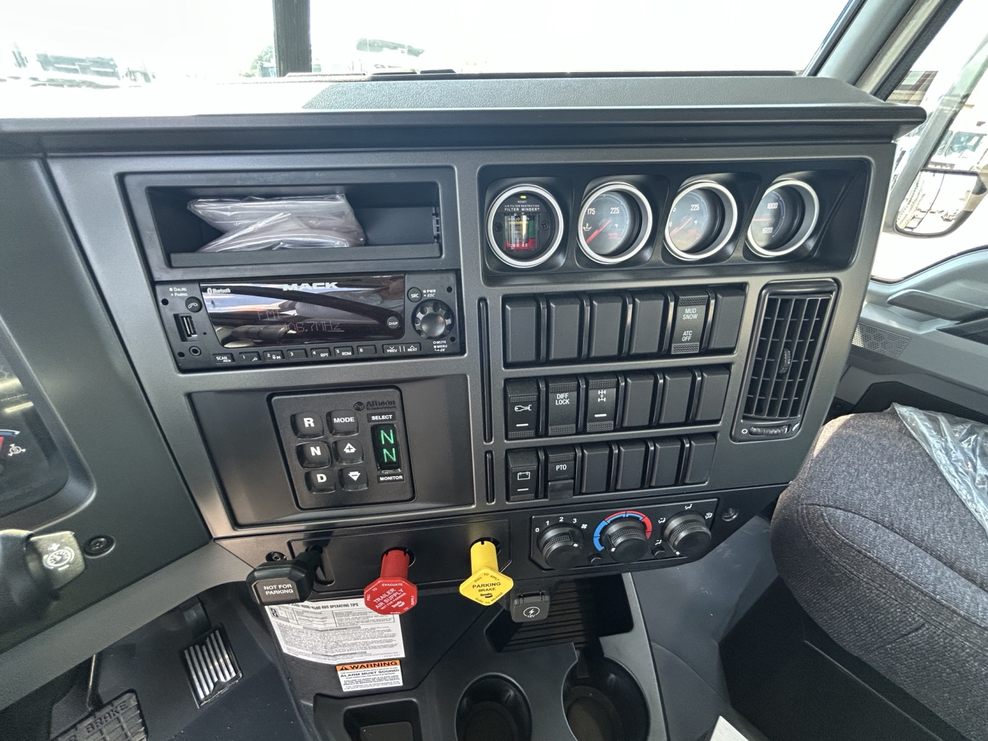 Dashboard and instrument cluster of a 2026 Mack GR64B roll-off truck interior showing gauge cluster, controls, and gear selector.