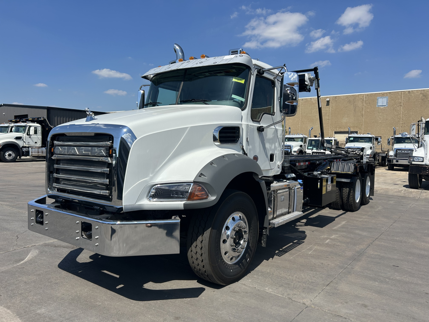 Mack GR64B rolling chassis truck in view showing front grille, chrome bumper, daytime running lights, dual rear wheels, and flatbed carrier.