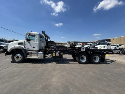 2026 Mack GR64B rolloff truck side view showing cab and flatbed with crane, VIN 1M2GR2GCXTM054673 visible on listing.