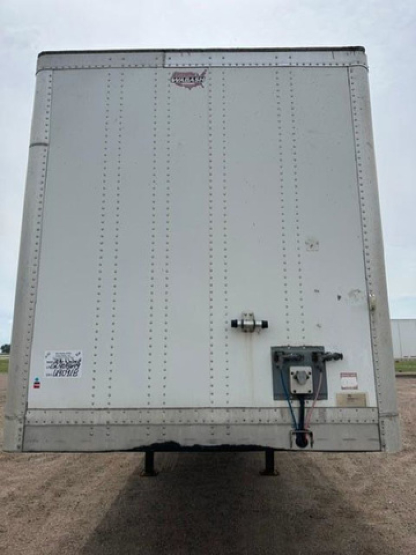 Rear view of a white 2016 Wabash van trailer showing a rear door, hinge ribs, locking handle, and undercarriage support legs.