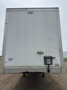 Rear view of a white 2016 Wabash van trailer showing a rear door, hinge ribs, locking handle, and undercarriage support legs.