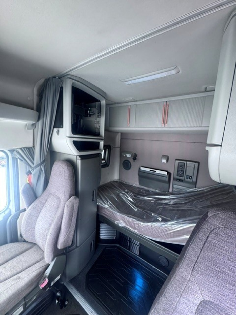 Interior cab of a 2021 Volvo VNL64T740 sleeper truck showing bunk area, overhead storage, and driver seat with protective plastic on the bed.