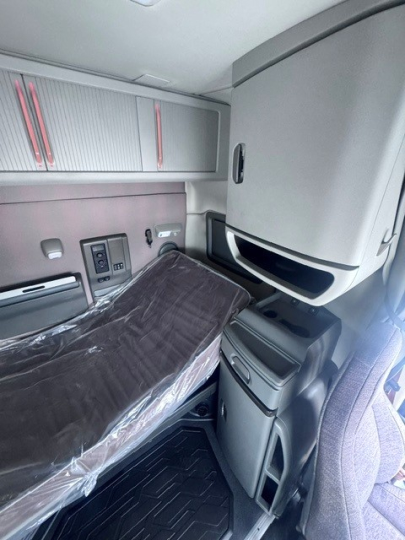 Interior of a Volvo VNL64T740 truck sleeper cab showing cabinets, storage compartments, and seat with control panels.