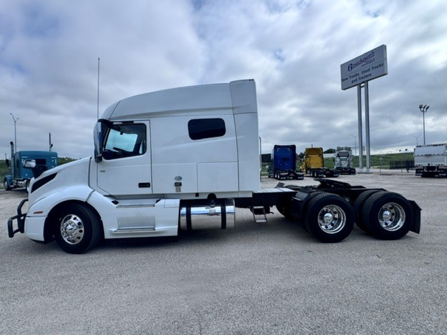 Truck cab side view showing 2021 Volvo VNL64T740 with sleeper, white exterior, dual rear axles, and chassis.