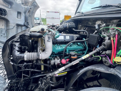 Volvo VNL64T740 engine bay showing diesel engine with turquoise coolant hose, black plastic intake, various colored wires, and engine components visible from the open hood.