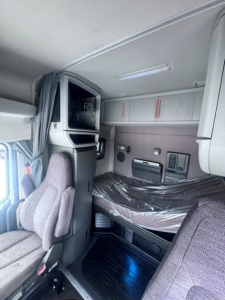 Interior cab of a 2021 Volvo VNL64T740 sleeper truck showing bunk area, overhead storage, and driver seat with protective plastic on the bed.