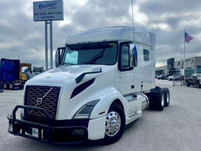 Volvo VNL64T740 sleeper cab tractor in white side view showing front grille guard and dual rear axles.