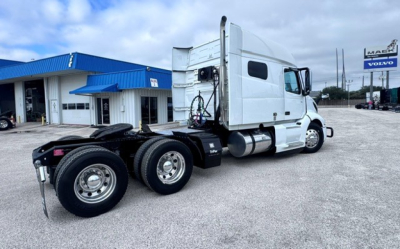 Volvo VNL64T740 sleeper tractor in service showing side cab and chassis with 6x4 rear wheels and fuel tanks.