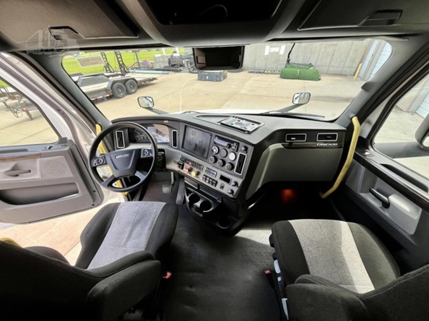 Freightliner Cascadia 126 cab interior showing steering wheel, dashboard with multiple gauges, center console, and seats.
