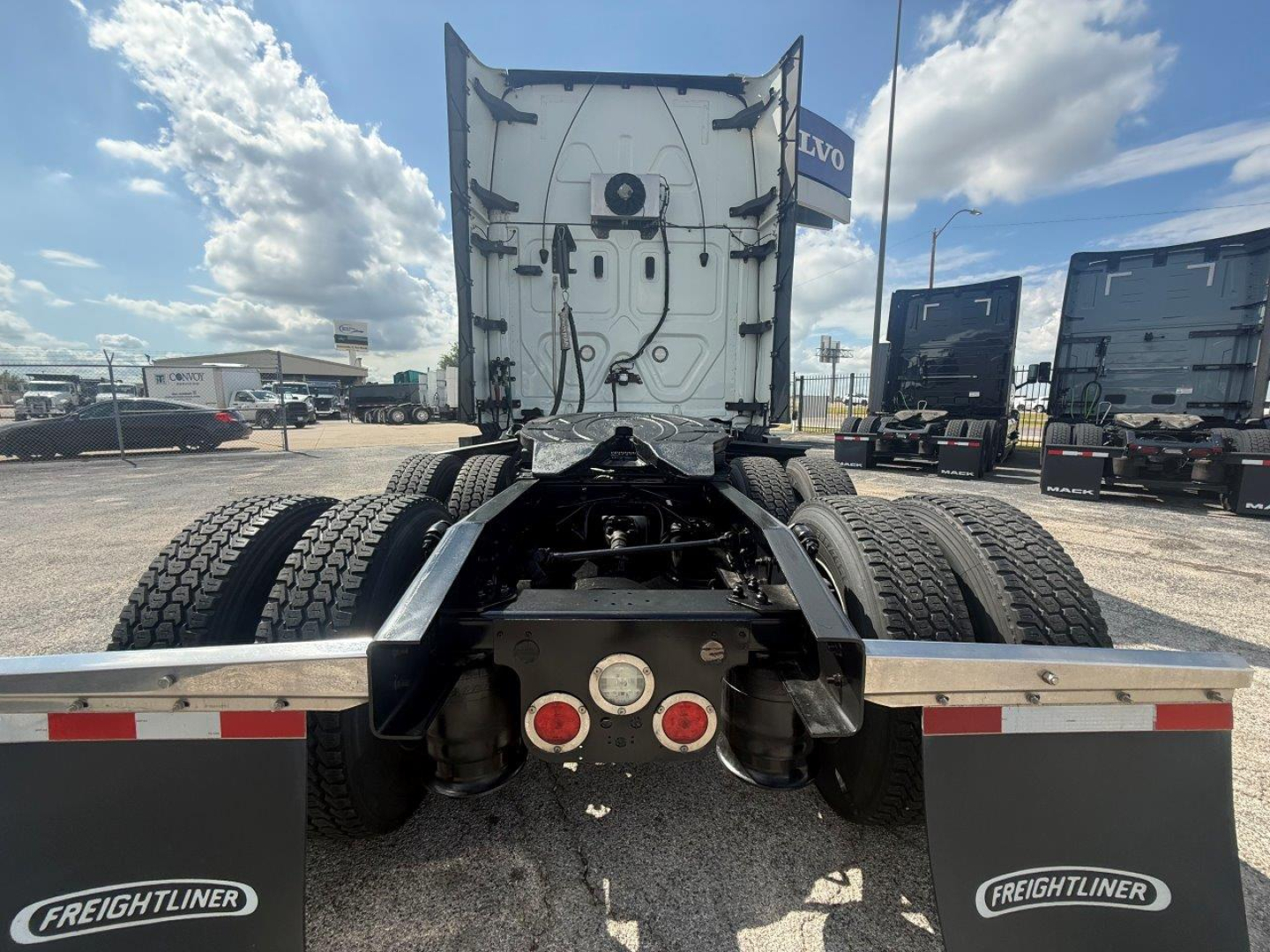Truck chassis rear view showing fifth wheel and dual rear axles with Freightliner branding on mud flaps and back of cab.