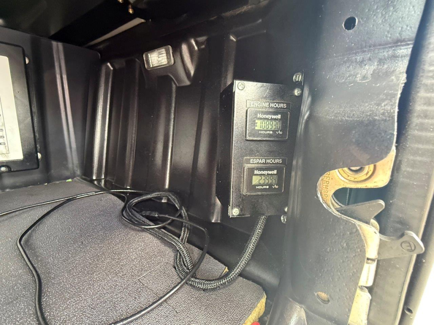 Truck interior side panel showing two Honeywell hour meters and wiring in the cab of a Freightliner Cascadia 126.