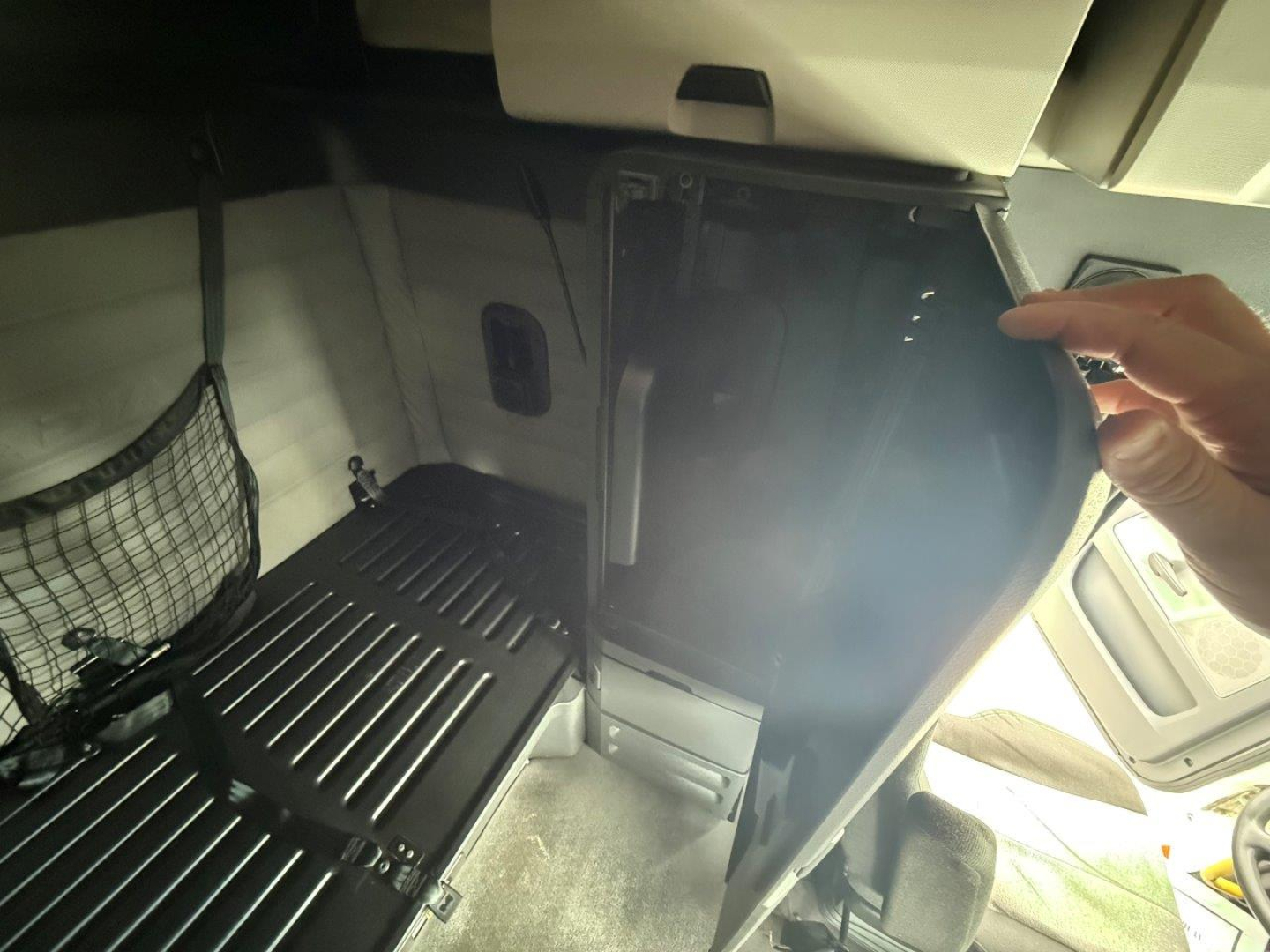 Freightliner Cascadia 126 truck interior sleeper area with storage drawers and partition; cabin view including seating area and overhead console.