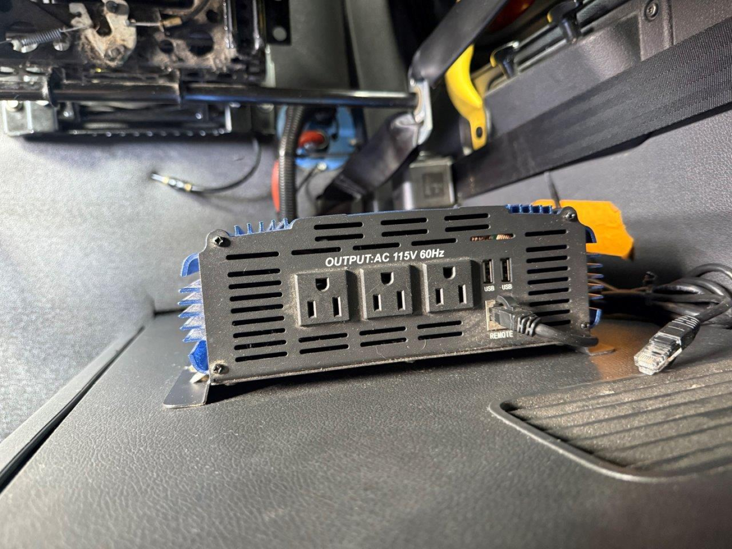 In-cabin electrical power inverter showing three AC outlets and USB port labeled OUTPUT AC 115V 60Hz inside Freightliner Cascadia dash area.
