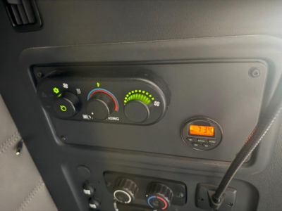 Dashboard of a Freightliner Cascadia 126 showing climate controls, digital gauge, and circular knob with orange display reading 17:34.