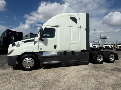 Freightliner Cascadia 126 sleeper cab truck left side view with white cab and black lower panels.