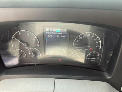 Dashboard cluster of a Freightliner Cascadia 126 showing instrument gauges and center display, with a navigation-like screen reading Engine Maintenance and 11208.9 hrs.