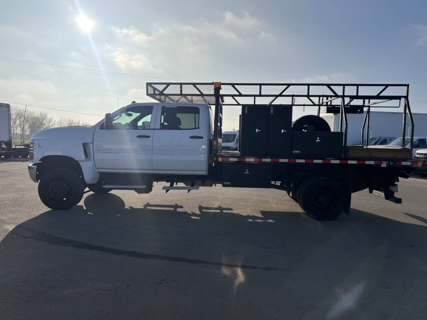 Truck side profile showing a white Chevrolet Silverado flatbed with utility racks and equipment on bed.